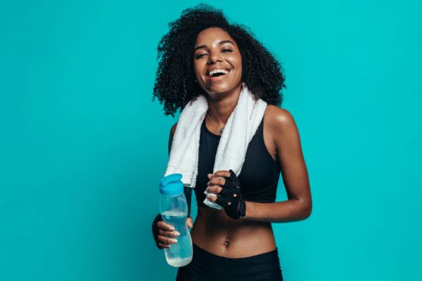 Young woman exercising with water bottle and towel.