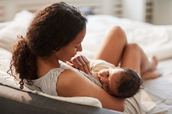 Young woman sitting up and showing how to breastfeed a newborn baby.