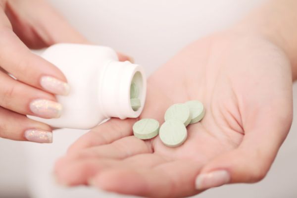 A woman with a bottle of tablets, illustrating antibiotics as treatment for many common vaginal infections.